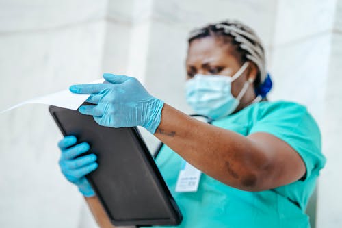 Free Ethnic physician in uniform with clipboard at work Stock Photo
