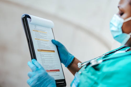 Free Side view of crop African American female medic in uniform reading text on paper at work Stock Photo