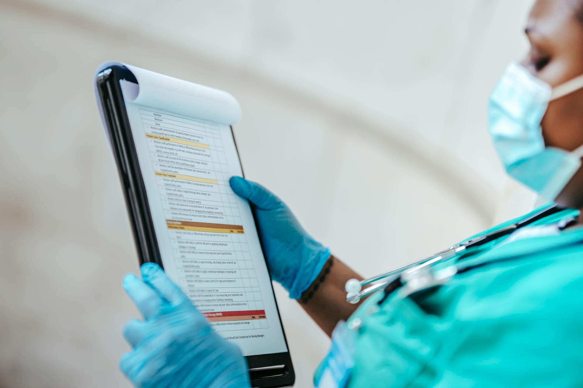 Side view of crop African American female medic in uniform reading text on paper at work