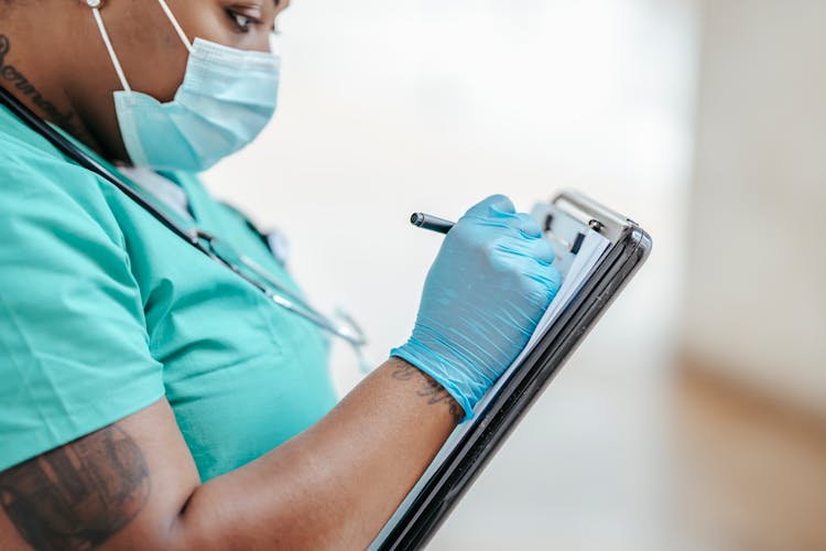 Crop Tattooed Black Physician Writing On Paper