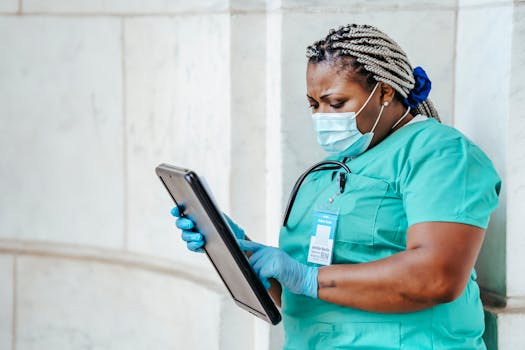 Focused middle aged ethnic female medic in uniform with clipboard and Afro braids in daylight