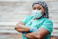 Self assured middle aged ethnic female medic in uniform with crossed arms looking at camera on street staircase