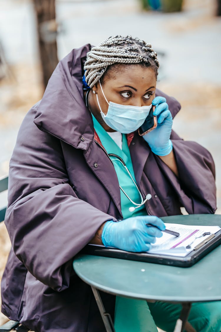 Attentive Black Doctor Speaking On Smartphone In City