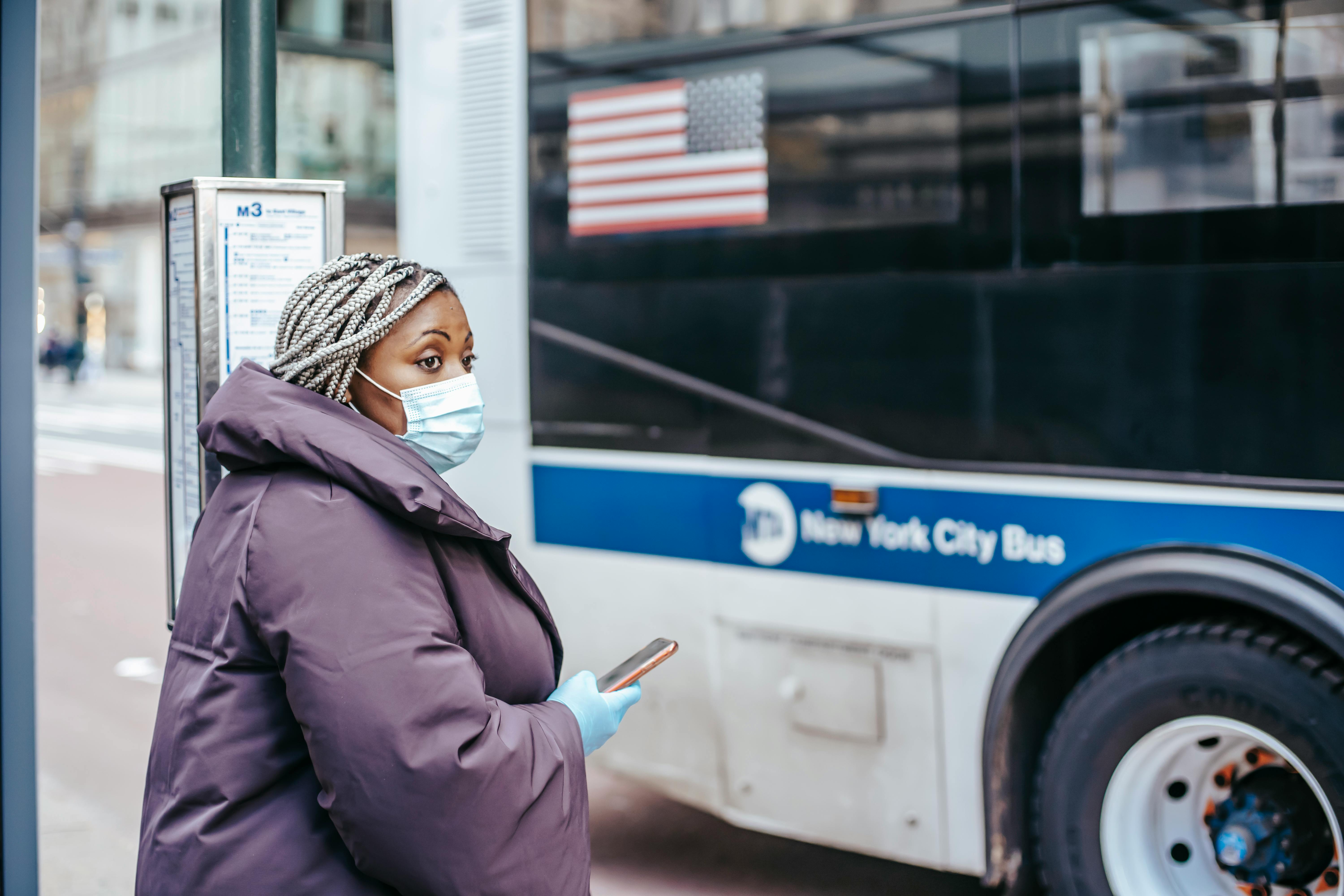 ethnic doctor with smartphone against urban bus