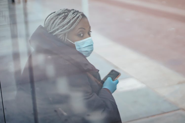 Black Doctor In Mask With Smartphone On Bus Stop