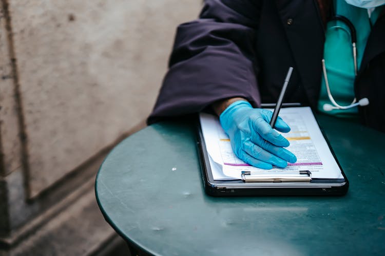 Crop Black Doctor With Document At Table