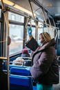 Side view of overweight ethnic female doctor in sterile mask and gloves looking forward in public transport