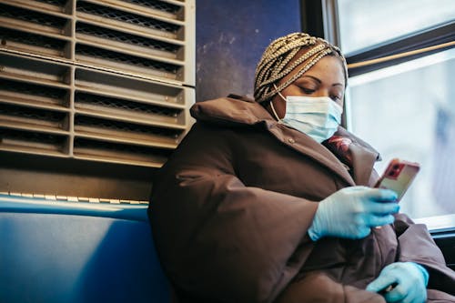 African American woman with phone riding bus in pandemic