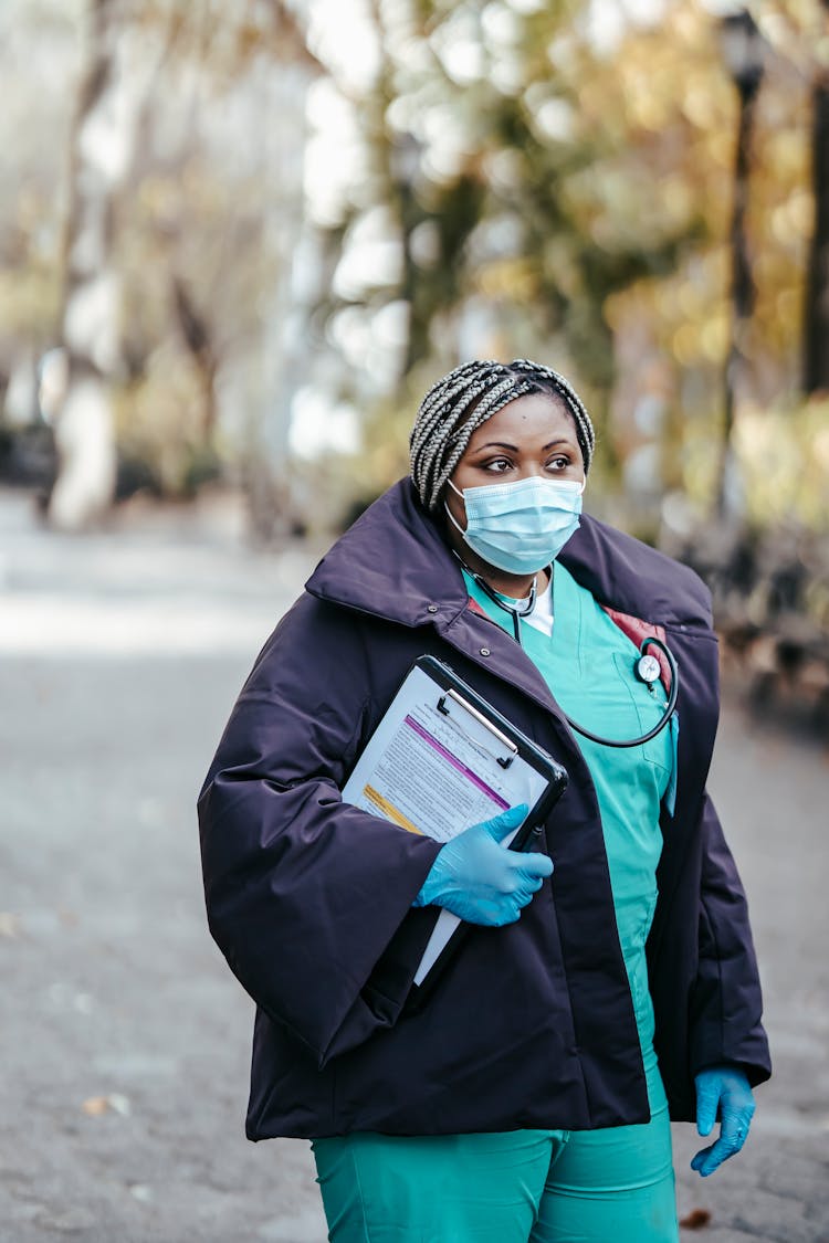 African American Woman Nurse Walking In Pandemic With Papers