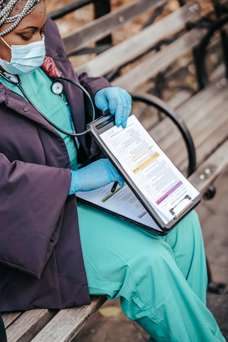 Black Lady Nurse Sitting With Documents In Coronavirus