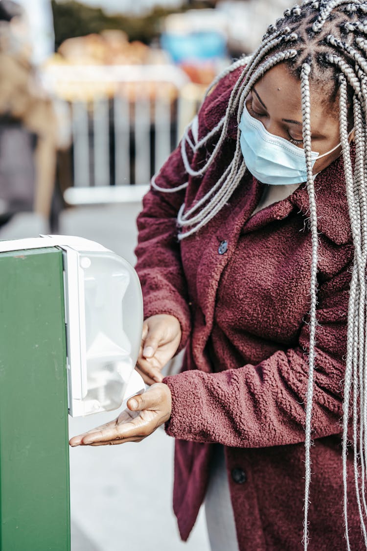 Black Female In Mask Using Sanitizer In Street