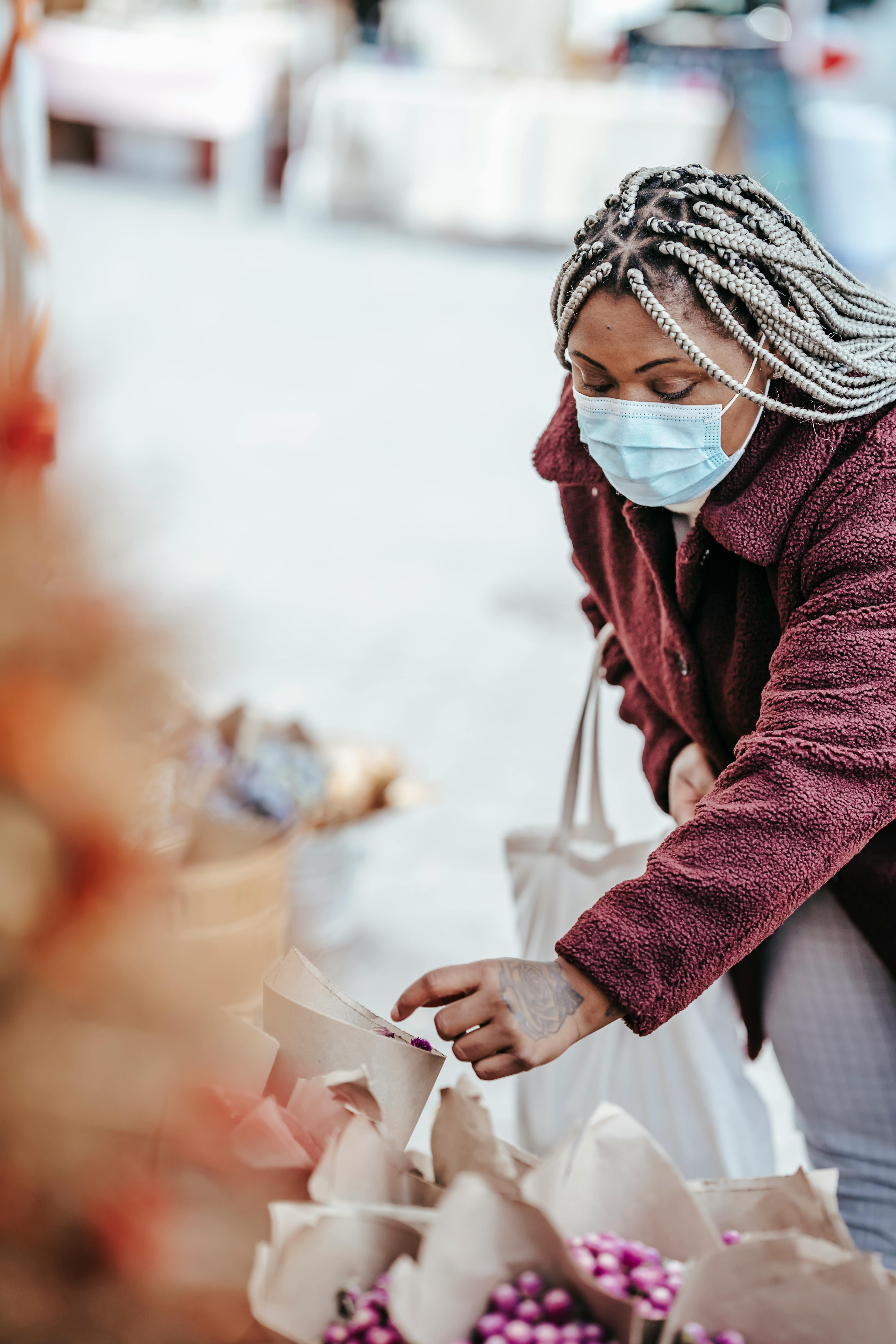 black woman picking bouquet of dry flowers in street