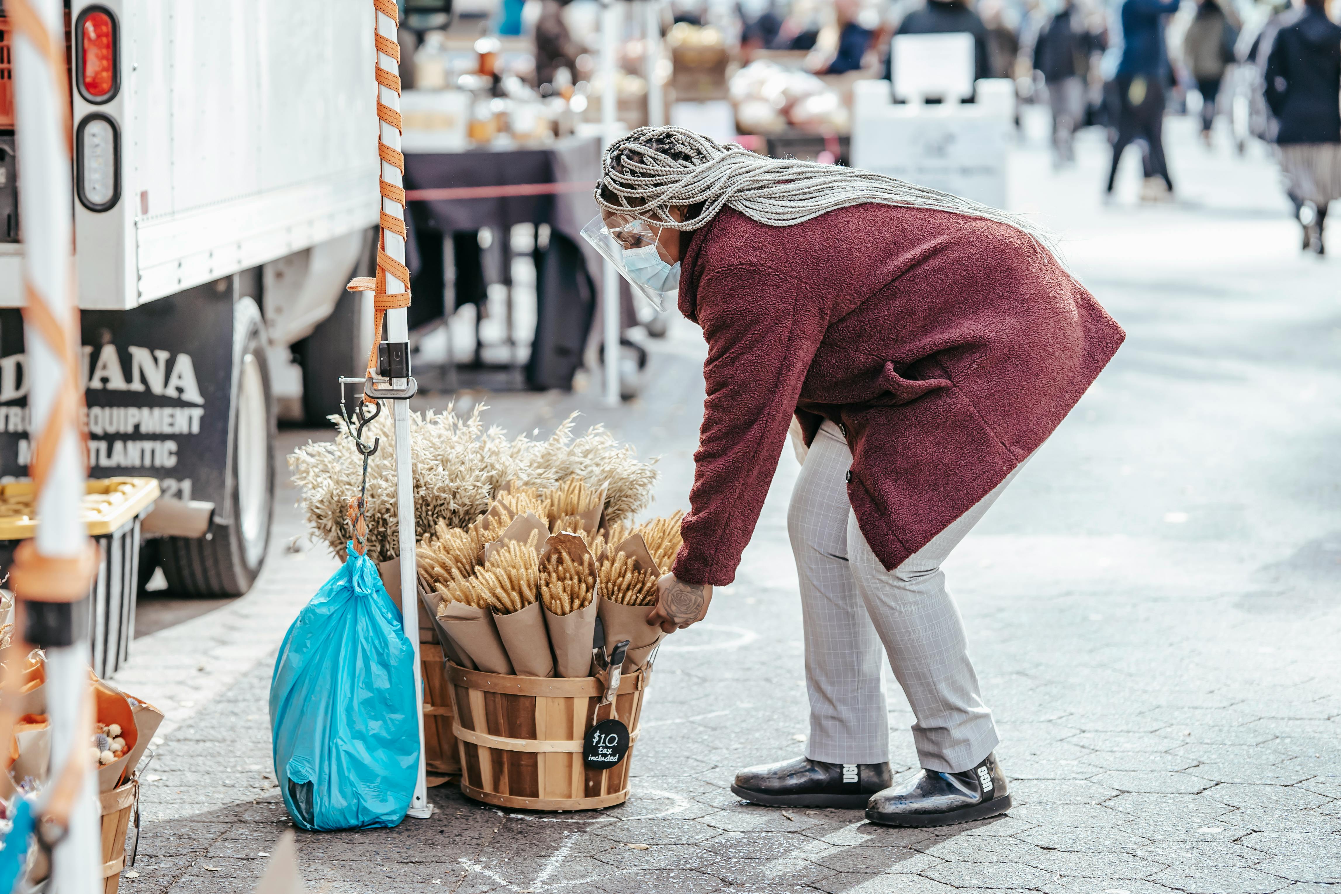 black female selecting bouquet of dried wheat in street