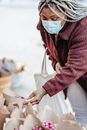 Black woman in mask choosing flowers on street market