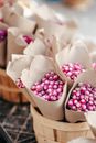 From above bouquets of little fresh pink flowers wrapped in paper placed in wooden baskets on street market at daytime