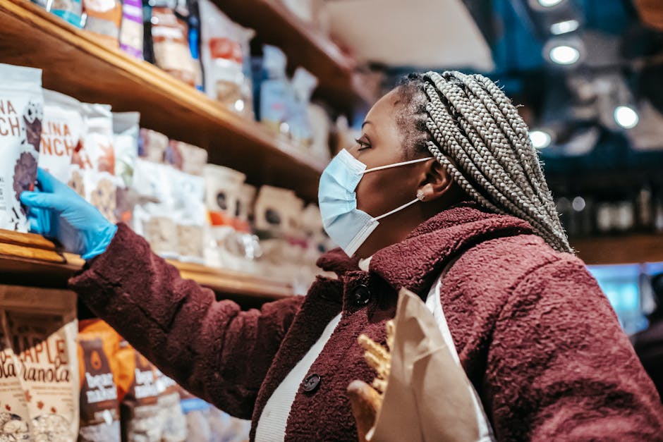 Side view of a woman wearing a mask and gloves shopping for groceries in a store.