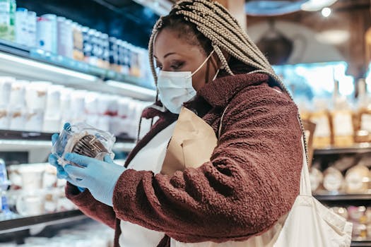 Woman wearing a mask and gloves shopping in a store, selecting products safely.