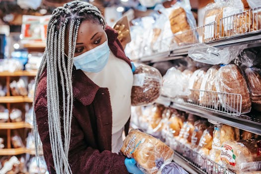 African woman selects bread in a grocery store during the COVID-19 pandemic, focusing on safety and choice.