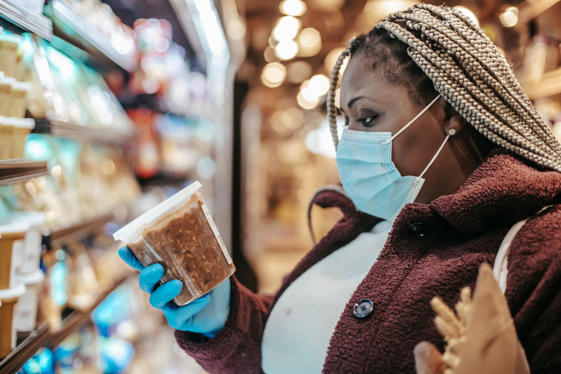 Shopper looking at ground beef prices in a grocery store meat aisle