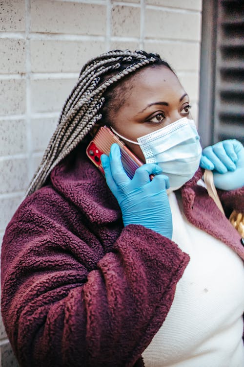 Free African American female wearing medical mask and latex gloves having conversation on mobile phone Stock Photo