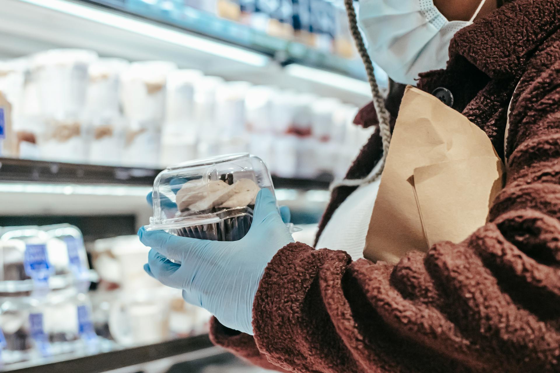 Anonymous black female in mask and gloves shopping in supermarket