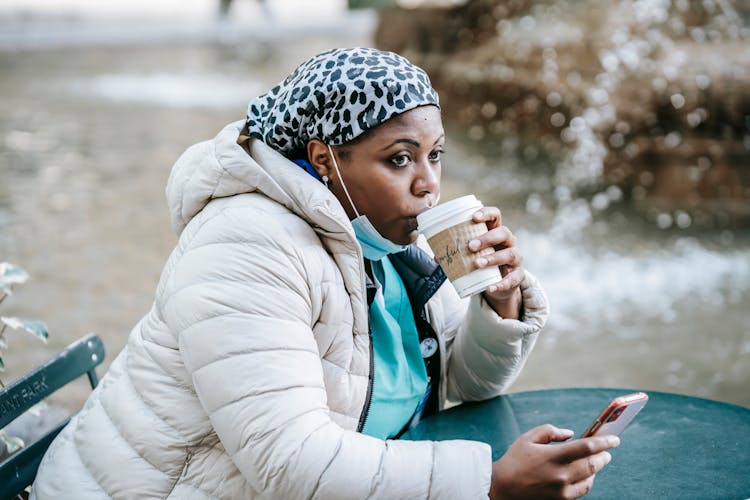 Adult Black Nurse Enjoying Takeaway Coffee In Outdoor Cafe