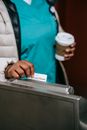 Crop faceless black nurse swiping pass card in metro turnstile