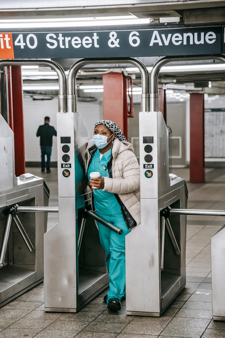 Adult Black Nurse Passing Turnstile In Metro Station