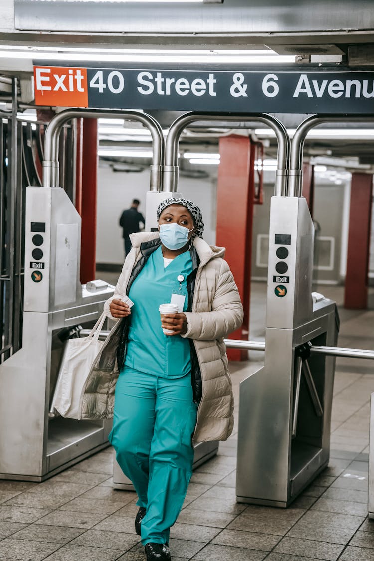 Black Nurse In Outerwear And Mask Leaving Metro Station