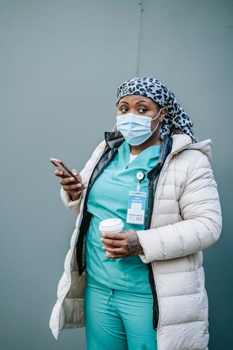 Calm Black Nurse In Mask Using Smartphone On Street