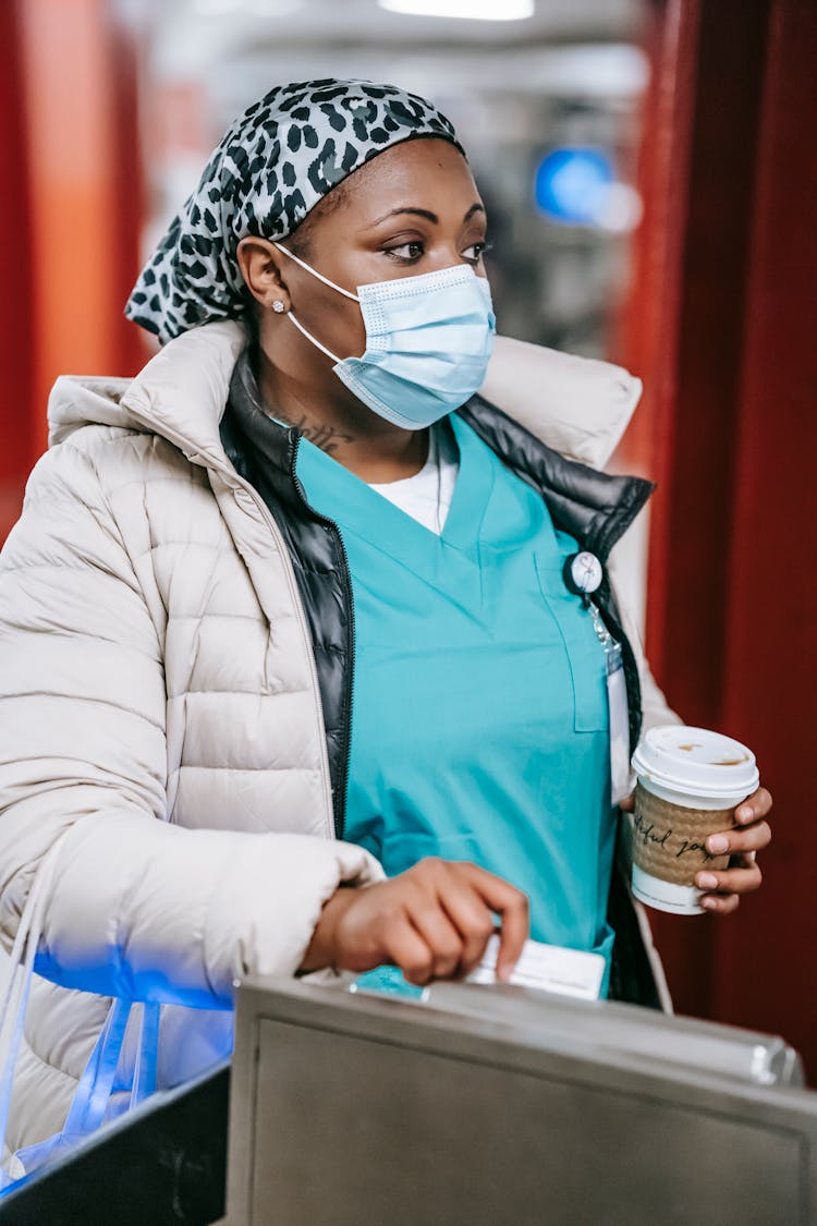 Calm Black Nurse In Mask Swiping Card And Passing Turnstile