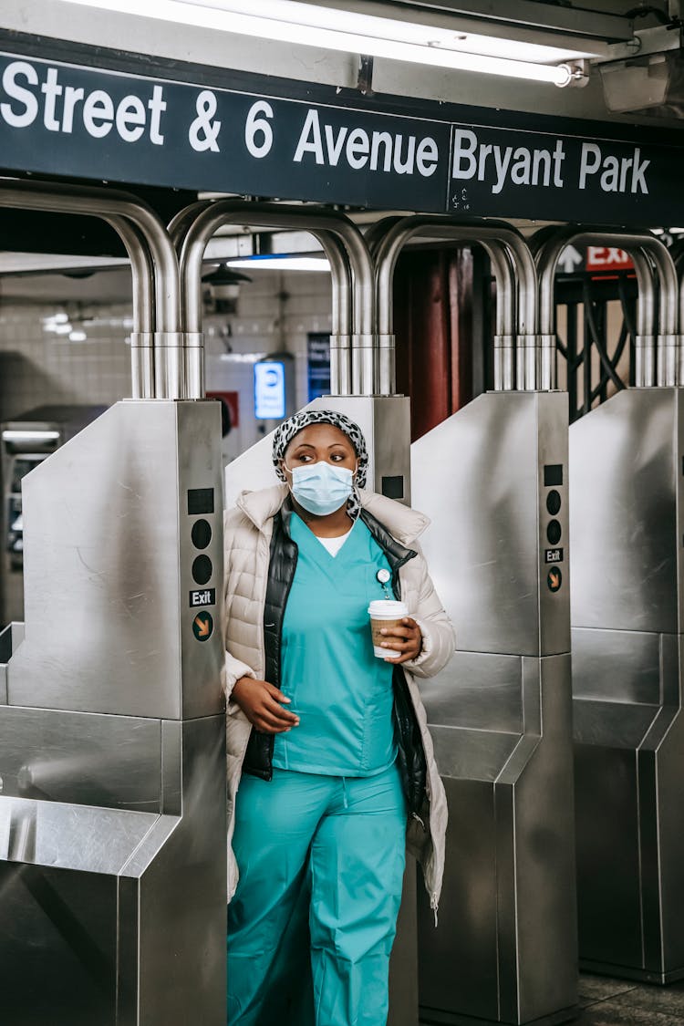 Adult Black Nurse Passing Through Turnstile In Metro Station