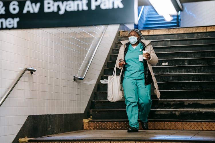 Black Nurse In Mask Walking In Metro Station Hallway