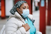 Pensive black nurse in mask standing in public place