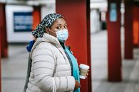 Black nurse in outerwear standing on metro platform