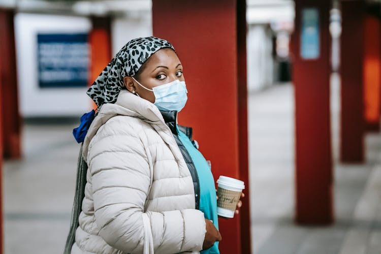 Black Nurse In Outerwear Standing On Metro Platform