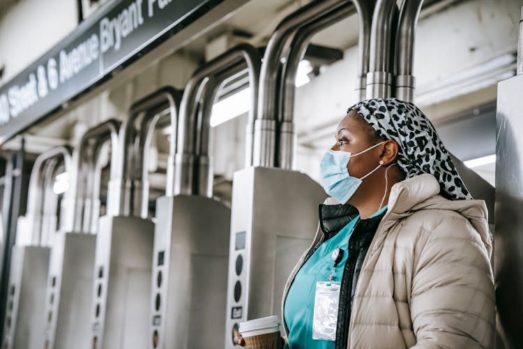 Calm Black Nurse In Mask Walking Through Turnstile In Metro