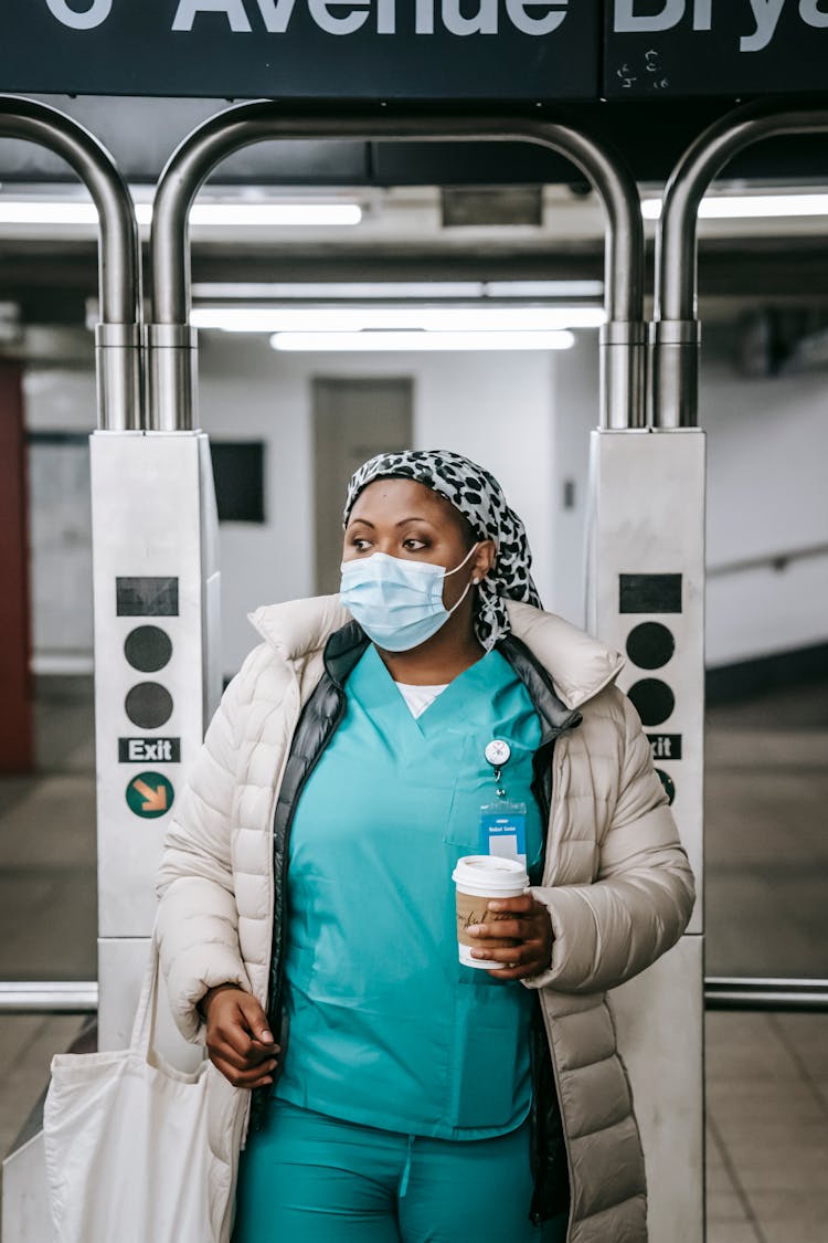 Black Nurse In Mask Going Through Turnstile In Underground