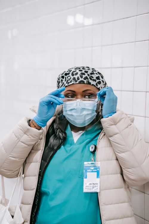 Free Focused African American female nurse in protective mask and latex gloves preparing for work in hospital Stock Photo