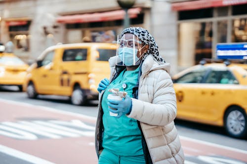 Black woman in mask with takeaway coffee