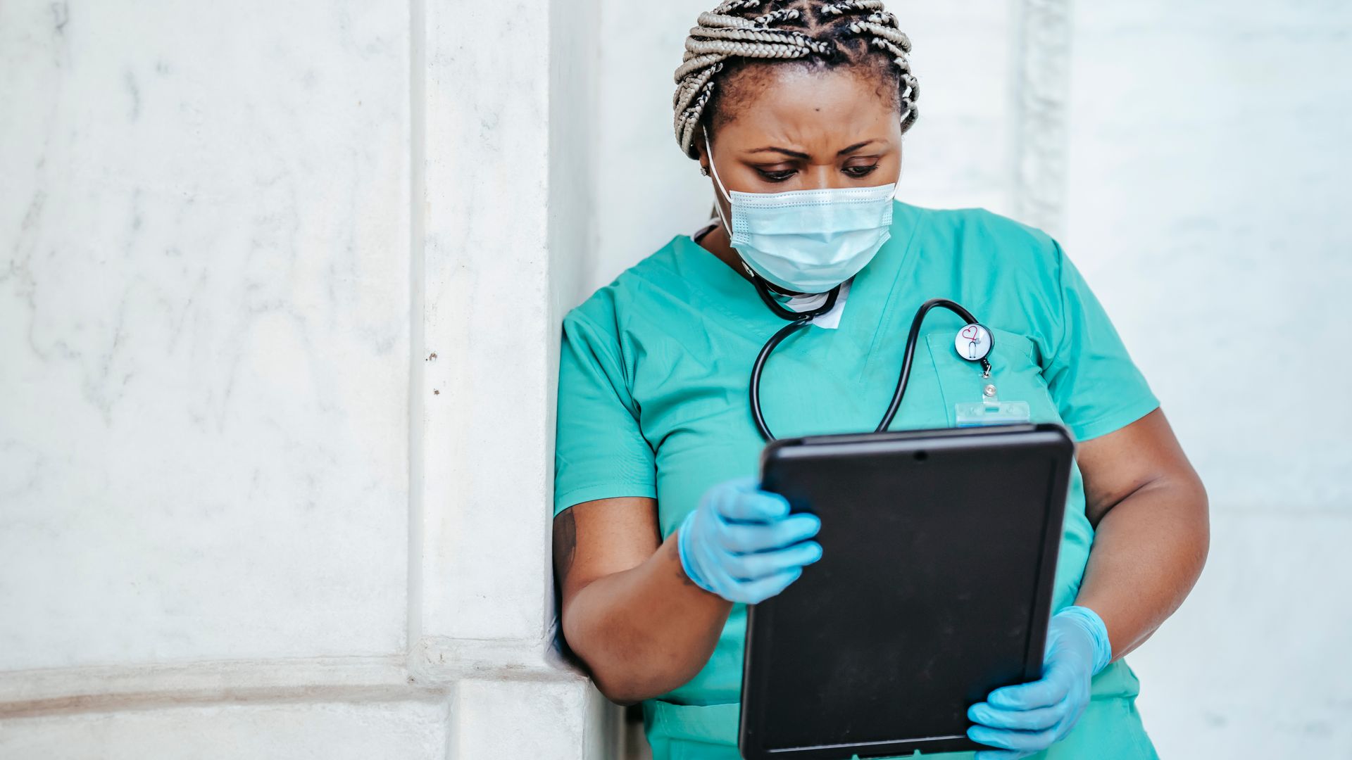 Modafinil for Nurses: Enhancing Alertness and Performance Concentrated African American female doctor in uniform and protective mask looking through documents in folder — modafinil for nurses