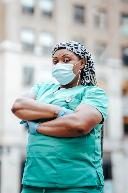 Black woman doctor in mask standing on street