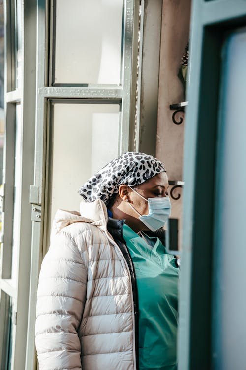 Pensive black woman doctor in mask standing in doorway