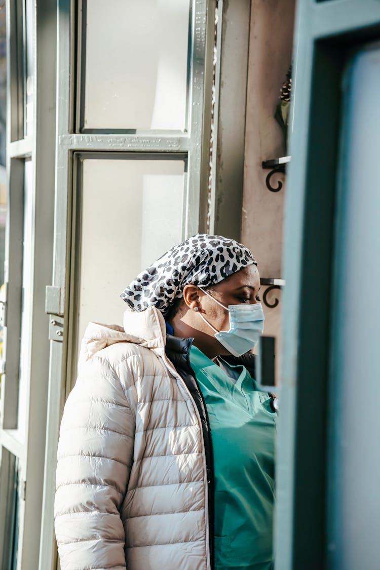 Pensive Black Woman Doctor In Mask Standing In Doorway