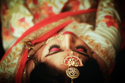 Close-up of an Indian bride in traditional attire with bridal jewelry and makeup.