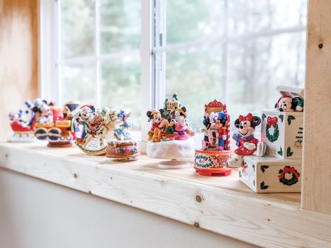 A collection of Mickey Mouse Christmas figurines decoratively arranged on a wooden window sill.