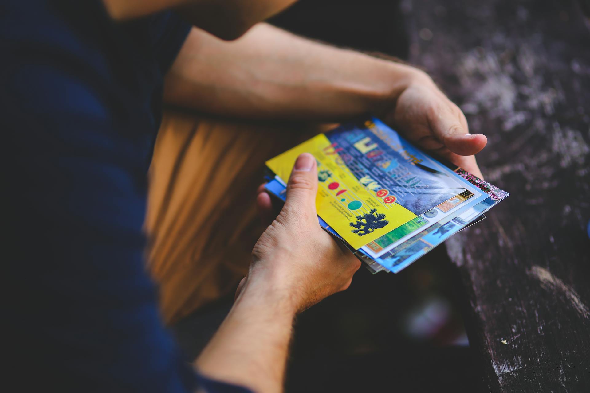 A person holding a collection of vibrant travel postcards outdoors.