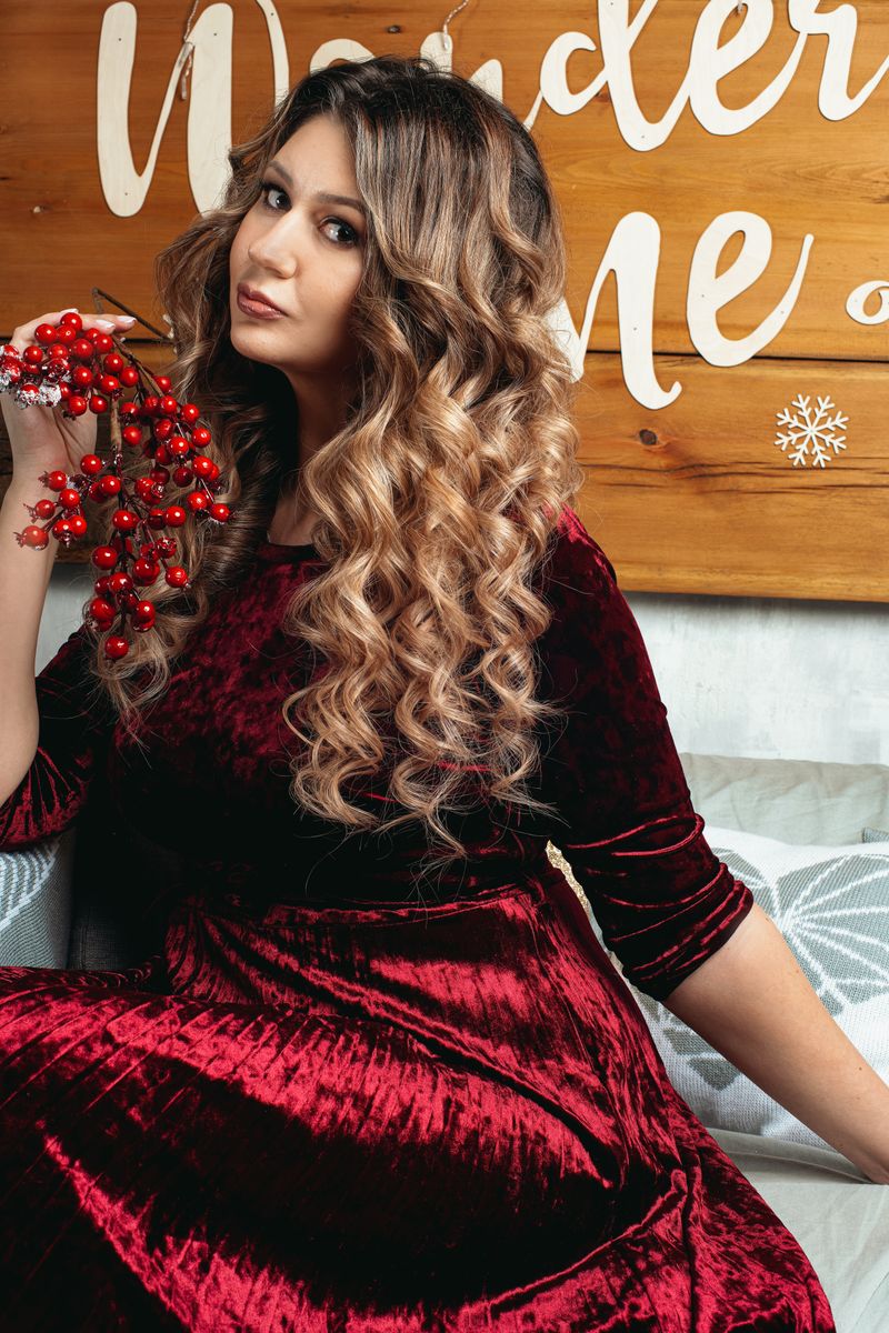 Woman in red velvet dress holding festive berries