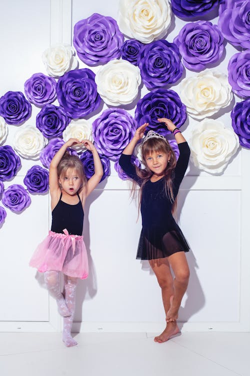 Free Two Girls Wearing Tutus Standing in Front of a Flower Wall Stock Photo