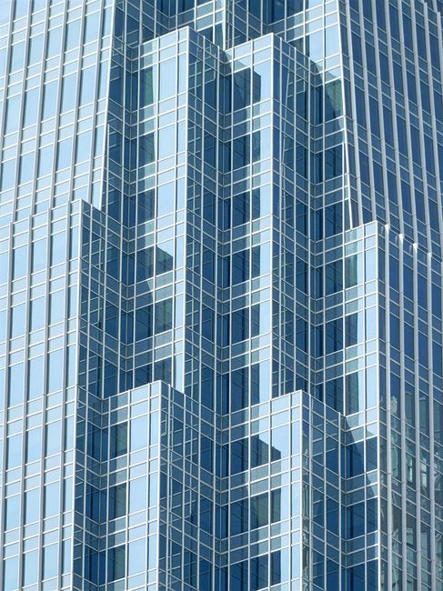 Low angle of high glass geometric contemporary construction with windows in city street